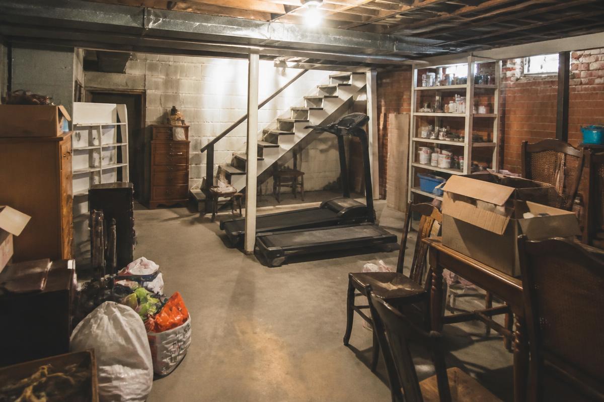 Basement packed with boxes, furniture, and an old treadmill before cleanout in Kings Mountain, NC