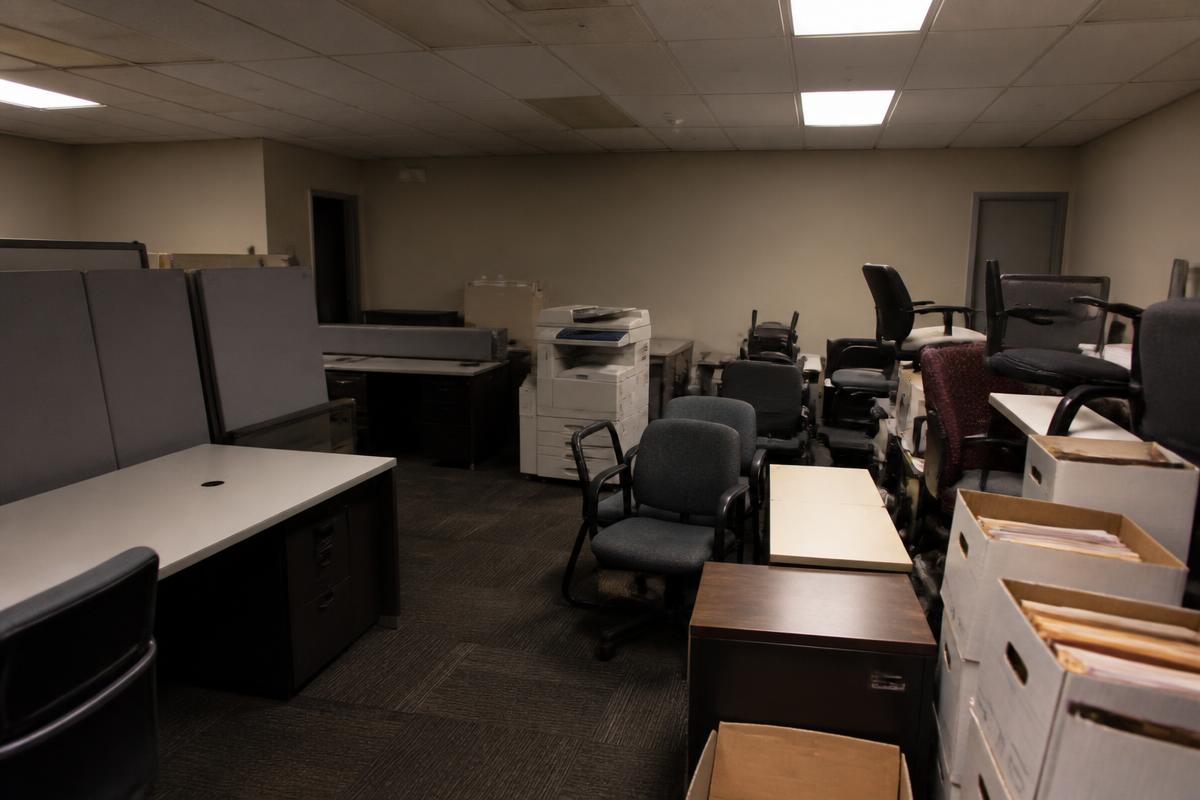 Vacated office suite full of old desks, chairs, and a copier before cleanout in Spindale, NC